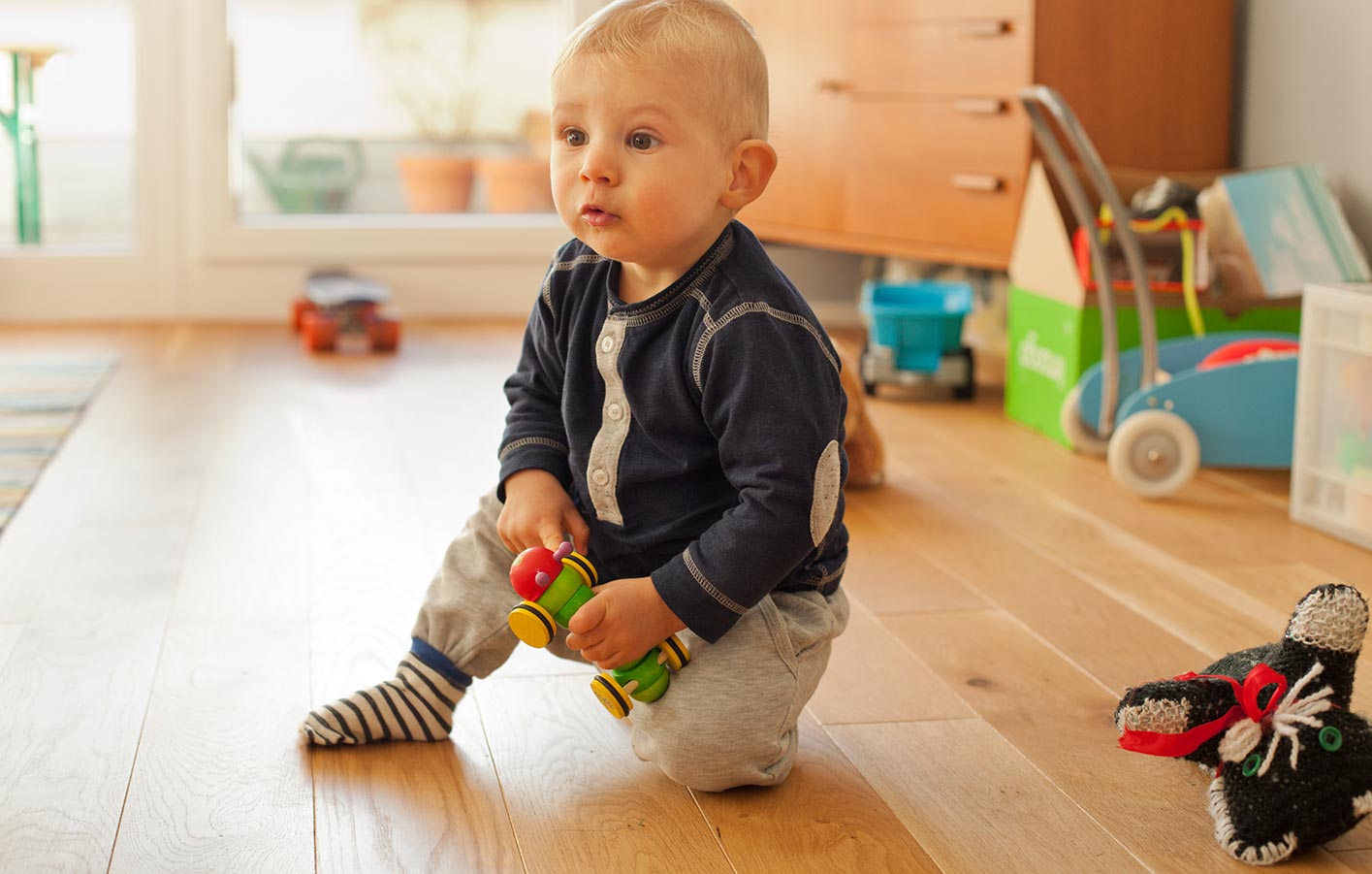 Baby sitzt auf Holzboden im Kinderzimmer